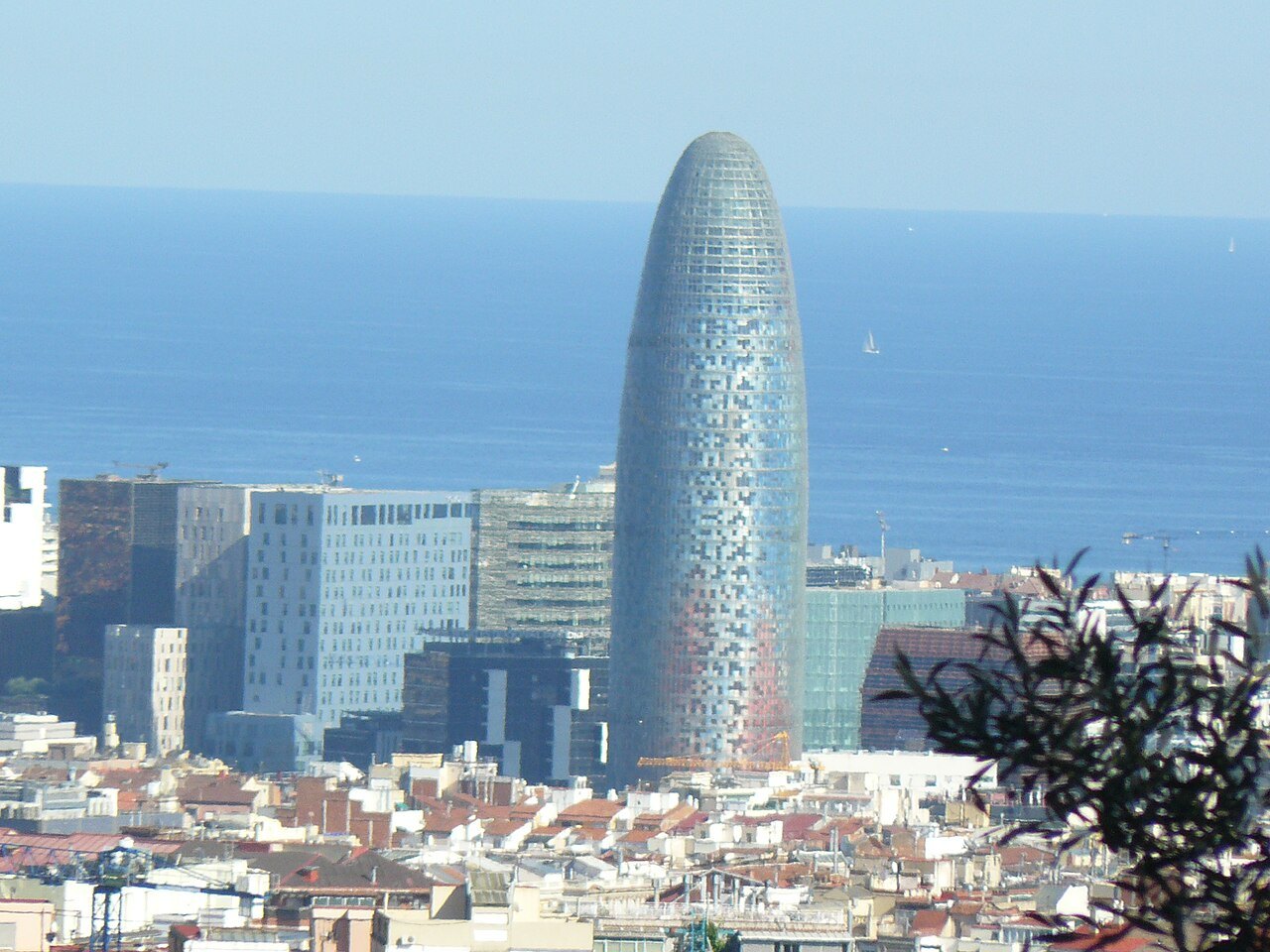 The Torre Glòries over the rooftops, with the sea beyond.